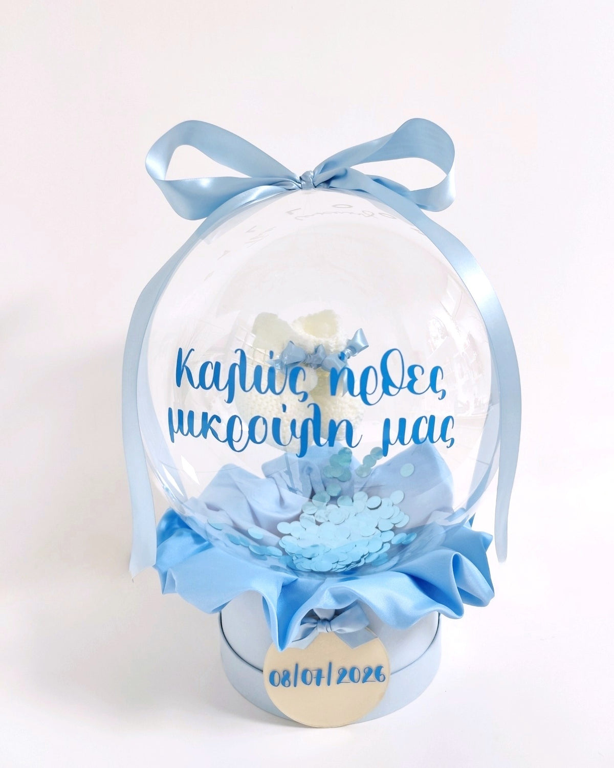 Πλεκτά βρεφικά καλτσάκια σε διάφανη σφαίρα με σιέλ κονφετί.